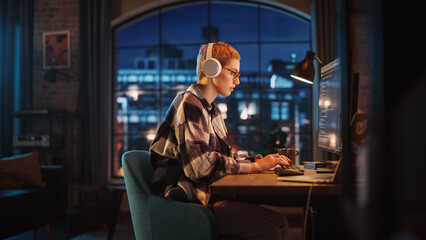 Young Woman Writing Code on Desktop Computer in Stylish Loft Apartment in the Evening. Creative...