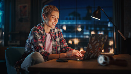 Young Attractive Woman Using Laptop Computer in Stylish Loft Apartment in the Evening. Creative...