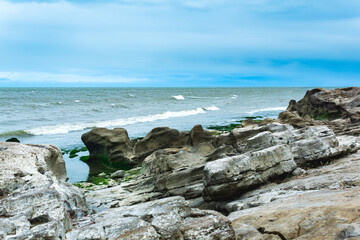 Fototapeta na wymiar gently sloping rocky shore of the Caspian Sea with rounded rocks and algae on the stones