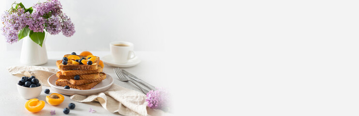 Trendy breakfast offer banner. Stack of delicious french toasts with berries, a cup of coffee and lilac flowers bouquet on white background. Copy space. Restaurant, backery web line.
