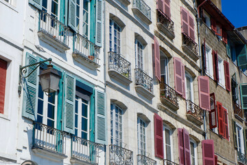 Fototapeta na wymiar Colourful classical facades with windows shutters and tiny balconies downtown Bayonne, French Basque country, France