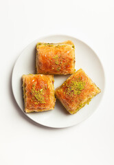 baklava with pistachios, 3 pieces, on a white plate, on a light background, view from above
