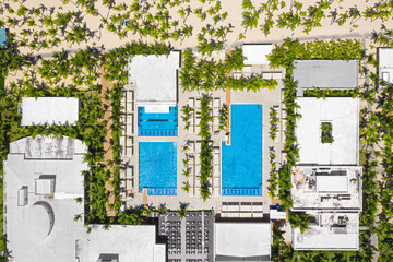 Outdoor poolside with swimming pools, coconut palm trees near sandy tropical beach. Caribbean travel. Aerial top view - obrazy, fototapety, plakaty