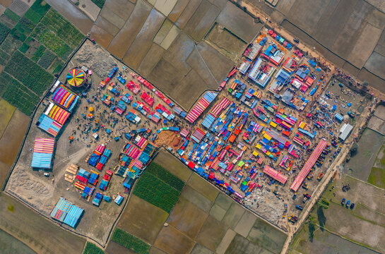 Aerial view of traditional village fair in Bangladesh. Colorful tents of temporary shops make it look like blocks of tetris game.  Portable ferris wheel