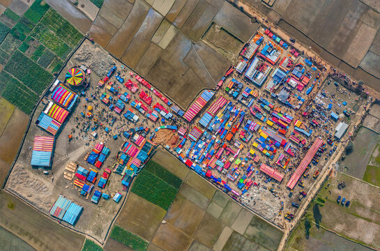 Aerial view of traditional village fair in Bangladesh. Colorful tents of temporary shops make it look like blocks of tetris game.  Portable ferris wheel