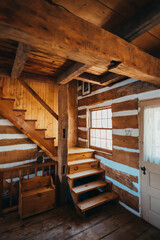 Interior of rustic log cabin home showing staircase and beams.