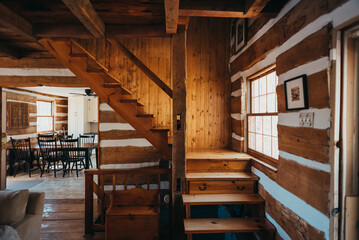 Interior of rustic log cabin home showing stairs and kitchen.