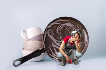 Humorous photo. A tired girl in an apron is squatting near a pil