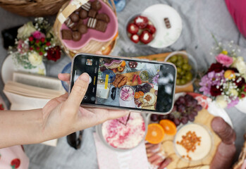 phone photographing charcuterie picnic food