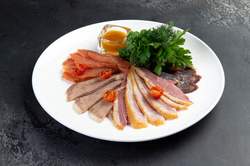 Meat delicacies on plate. On a gray background.