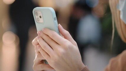 Close-up female hands holding smartphone. Unrecognizable girl in medical mask woman using phone swipe on smartphone texting with doctor covid consultation online makes payment purchase in mobile app - Powered by Adobe