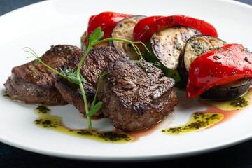 Beef medallions and grilled vegetables. On a gray background.