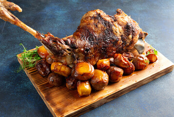 Cooked leg of lamb and new potatoes. On a gray background.