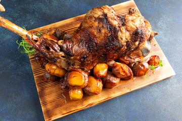 Cooked leg of lamb and new potatoes. On a gray background.