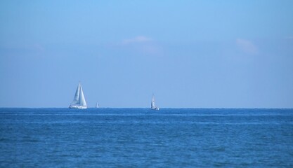 Barcos de vela navegando en el horizonte en la playa de la Malvarrosa en Valencia, España. El mar...