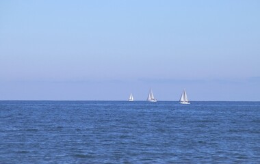Barcos de vela navegando en el horizonte en la playa de la Malvarrosa en Valencia, España. El mar...