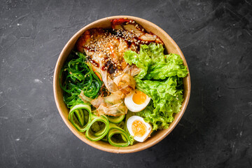 delicious poke bowl with fresh vegetables and seafood on a black background