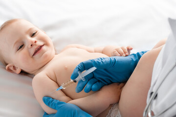 Doctor vaccinating baby in clinic. Little baby get an injection. Pediatrician vaccinating newborn...