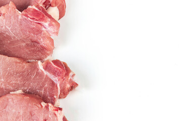 Sliced raw pork meat in row with spices on white background with copy space.
