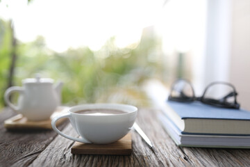 White coffee nd teapot and notebooks and black glasses on wooden table outdoor balcony