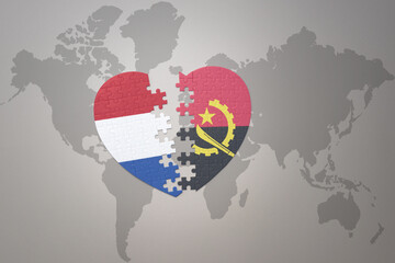 puzzle heart with the national flag of angola and netherlands on a world map background.Concept.