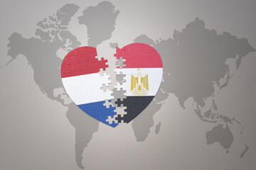 Fototapeta premium puzzle heart with the national flag of egypt and netherlands on a world map background.Concept.