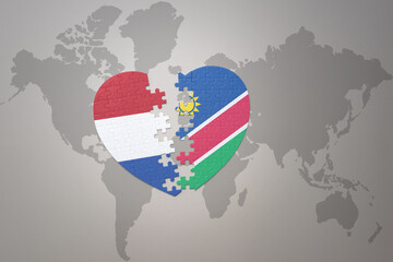 puzzle heart with the national flag of namibia and netherlands on a world map background.Concept.