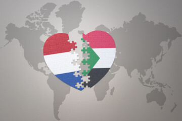 puzzle heart with the national flag of sudan and netherlands on a world map background.Concept.