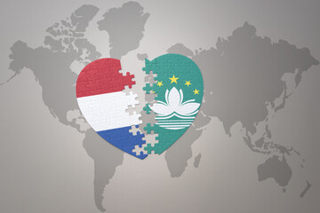 puzzle heart with the national flag of Macau and netherlands on a world map background.Concept.