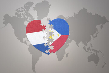 puzzle heart with the national flag of philippines and netherlands on a world map background.Concept.