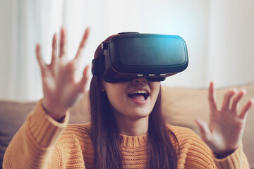 Exciting asian woman with wearable VR headset playing sport gaming online in living room at home.