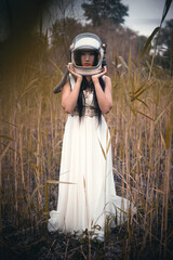 Fototapeta premium Young girl in the space helmet and white dress outdoors. Other planet journey concept.