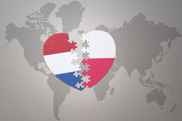 puzzle heart with the national flag of poland and netherlands on a world map background.Concept.