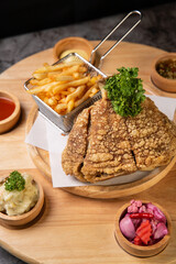 Pork knuckle Served with french fries and mashed potatoes on wooden cutting board