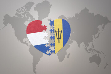 puzzle heart with the national flag of barbados and netherlands on a world map background.Concept.