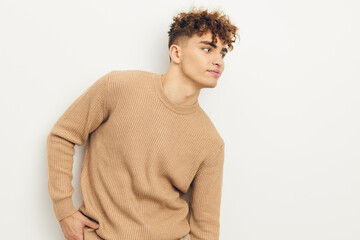 horizontal photo of a cute, neutrally emotional man in a beige sweater looking towards an empty space