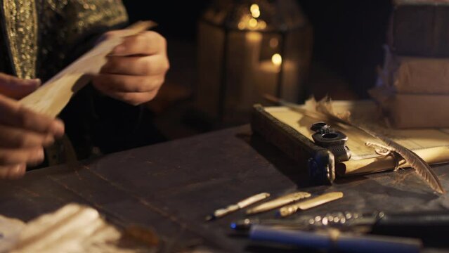Arabic script in ancient times. The man who wrote the letter. Writing on parchment paper in the historical period. Pen made of ivory. Old era inkwell.