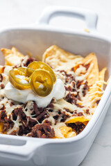 nachos with beef minced meat and cheese served with whipped cream and jalapenos