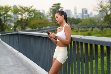 Young fitness woman in sportswear using smart phone while exercising in city park, Healthy and Lifestyles.