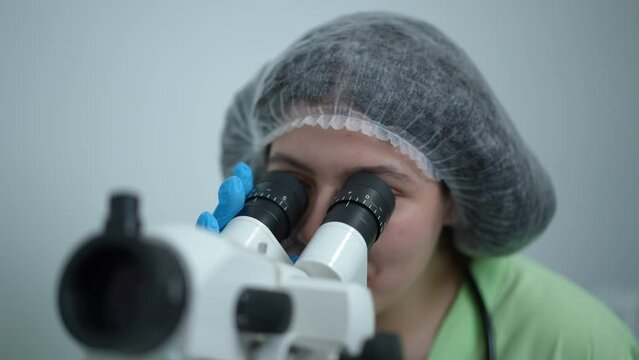 Close-up portrait of smiling confident gynecologist using colposcope sitting in hospital indoors. Professional Caucasian woman examining cervix vagina and vulva with gynecological equipment