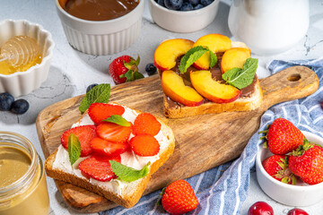 American European summer breakfast sandwiches, toasts with peanut butter, chocolate and cream cheese with berry and fruits, top view flatlay on kitchen table