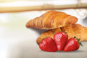 Tasty sweet Croissant with fresh strawberry on the desk