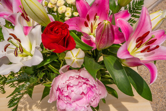 Close up of colorful bouquet - pink peonies, purple and white lily flowers, red roses. High quality photo