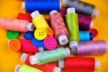 Set of multicolored buttons and Spools threads on a yellow background. Blurring.