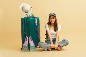 Happy Asian young woman smilling and sitting on the floor with luggage nearby with fun stuff for trip traveling.