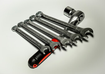 Five spanners leaned against ratchet with a red handle on a white background.
