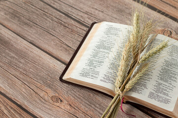 Ripe spring barley and an open Holy Bible Book on a rustic wooden table. Copy space. Wave sheaf...