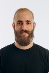 portrait of a young guy with a beard in a black T-shirt on a white background. hipster