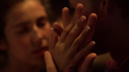 Closeup lovers hold hands together on date. Romantic couple touch fingers.