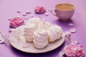 Natural homemade vanilla sugar free marshmallows with cup of coffee. Healthy sweets, natural food. Romantic purple background with tea rose decorations.